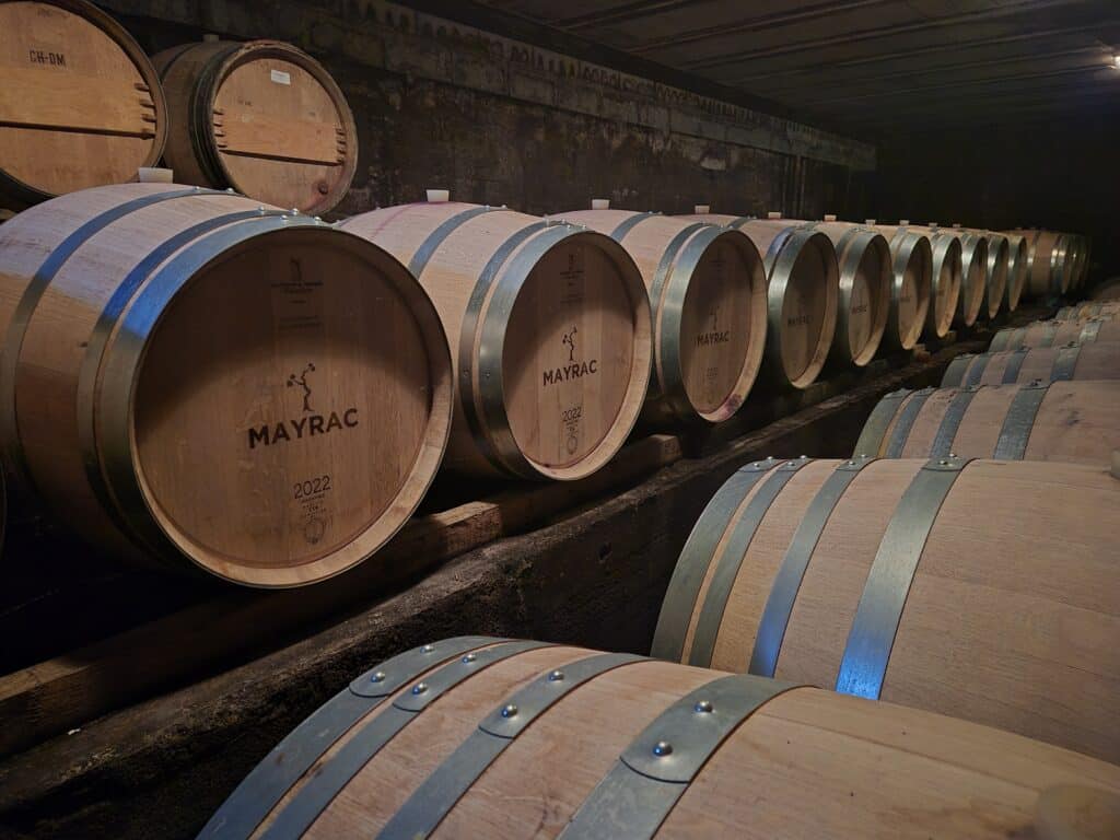 Barriques Mayrac 2022 : Cave à Vin et Vieillissement Barriques en chêne Mayrac 2022 alignées dans une cave sombre pour le vieillissement du vin.
